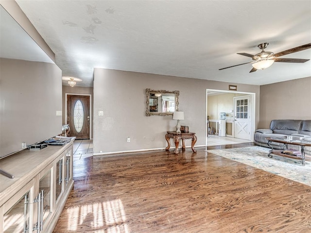 living area featuring baseboards, wood finished floors, and ceiling fan