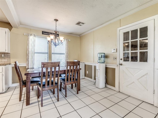 dining space with visible vents, an inviting chandelier, light tile patterned floors, and crown molding