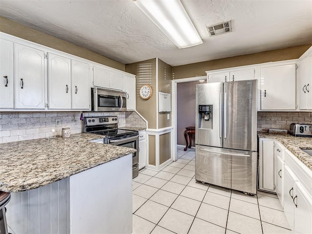 kitchen with backsplash, stainless steel appliances, visible vents, and white cabinets