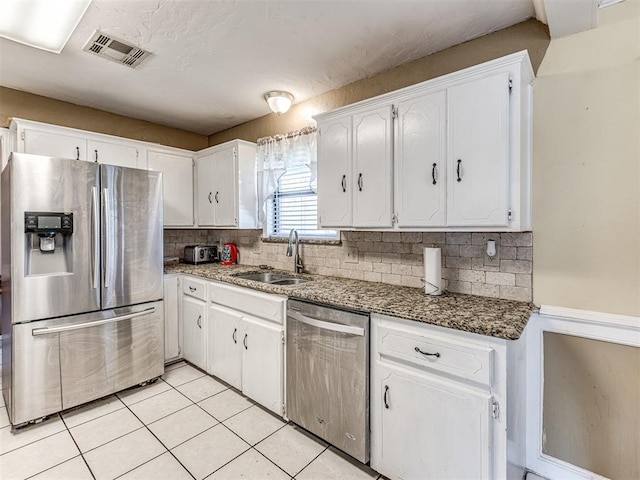 kitchen with white cabinets, stainless steel appliances, a sink, visible vents, and light tile patterned floors