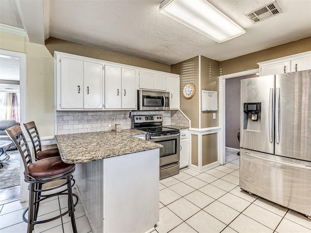 kitchen featuring backsplash, visible vents, white cabinetry, and appliances with stainless steel finishes