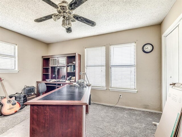 carpeted office space with a textured ceiling and ceiling fan