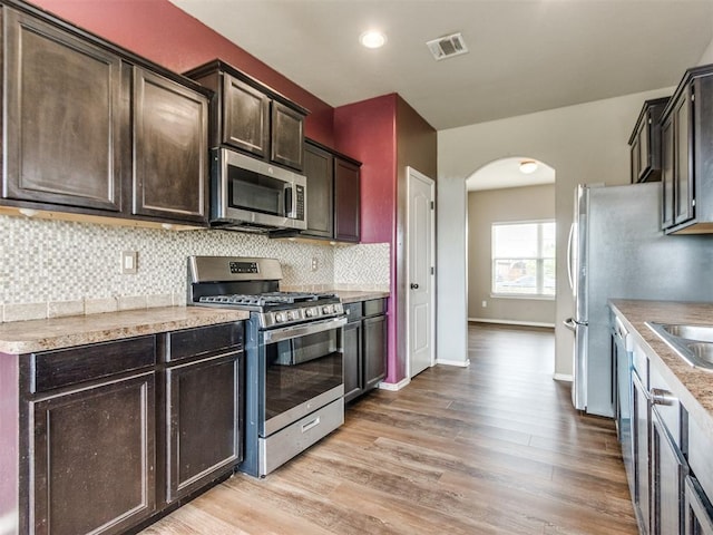 13309 Beaumont Dr, Piedmont, OK 73078 - kitchen featuring visible vents, light wood-style floors, tasteful backsplash, arched walkways, and appliances with stainless steel finishes