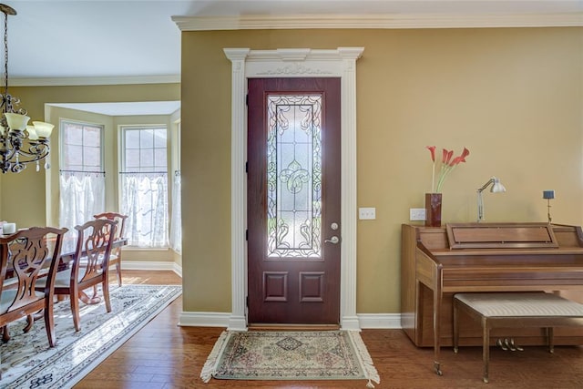 entryway featuring a chandelier, wood finished floors, baseboards, and ornamental molding