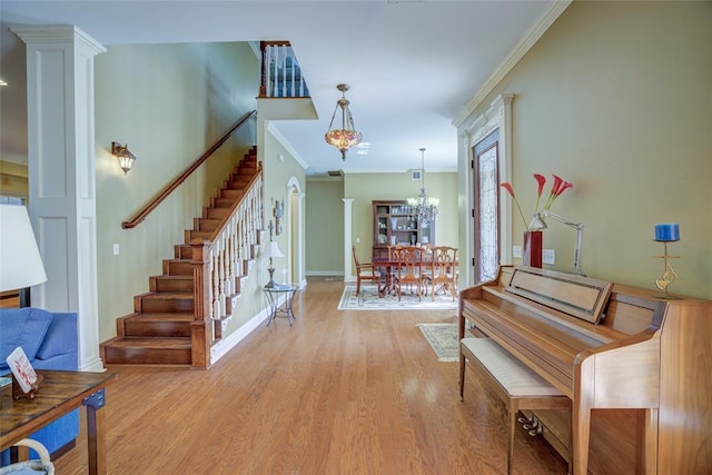 entrance foyer with stairs, ornamental molding, wood finished floors, and ornate columns