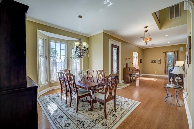 dining space with an inviting chandelier, visible vents, ornamental molding, light wood-type flooring, and baseboards