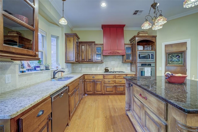 kitchen featuring stainless steel appliances, light wood-style flooring, visible vents, brown cabinets, and premium range hood