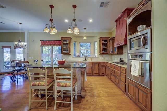 kitchen with crown molding, a center island, stainless steel appliances, a notable chandelier, and visible vents