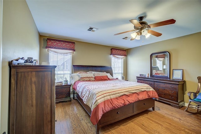 bedroom with light wood-type flooring, a ceiling fan, and visible vents