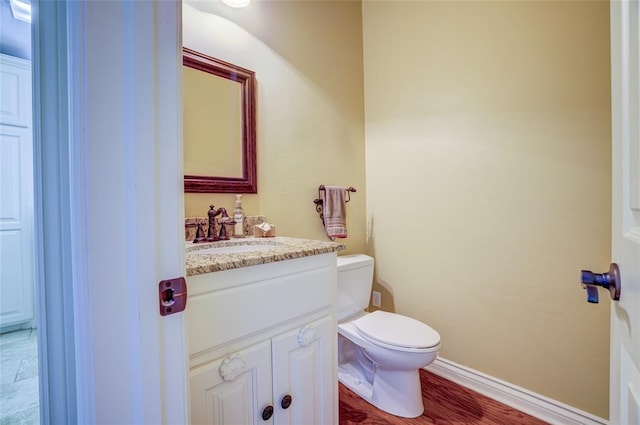 bathroom featuring baseboards, toilet, and vanity