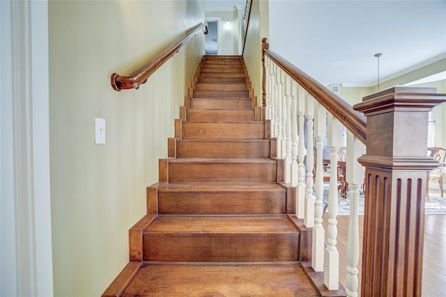 stairs featuring wood finished floors, visible vents, and crown molding
