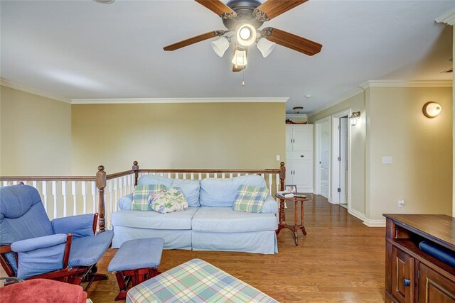 living room featuring wood finished floors, crown molding, baseboards, and ceiling fan