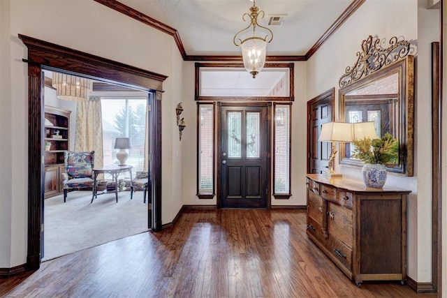 foyer entrance with an inviting chandelier, ornamental molding, wood finished floors, and visible vents