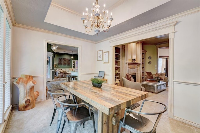 dining space with a fireplace, ornamental molding, light carpet, and a chandelier