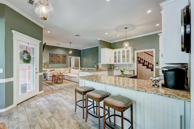 kitchen featuring stainless steel dishwasher, white cabinetry, a peninsula, glass insert cabinets, and light wood-style flooring