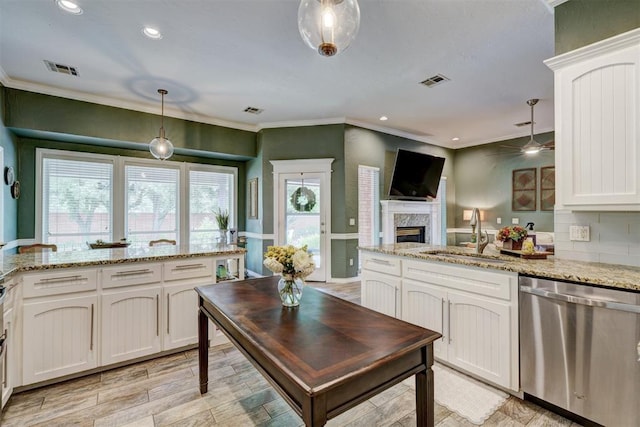 kitchen with a sink, a fireplace, a peninsula, stainless steel dishwasher, and visible vents