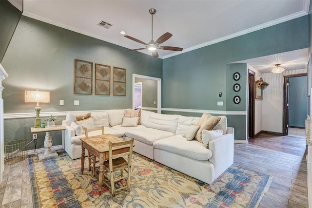 living room featuring a ceiling fan, visible vents, crown molding, wood finished floors, and baseboards