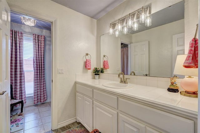 full bathroom featuring vanity, tile patterned flooring, and a textured wall