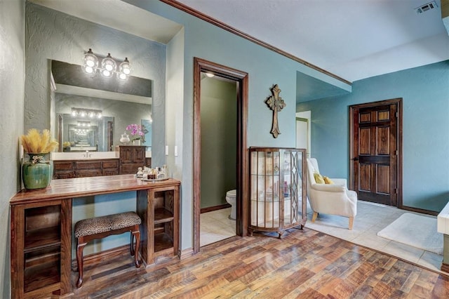 interior space featuring visible vents, wood finished floors, baseboards, vanity, and toilet