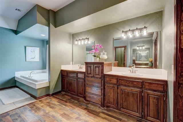 bathroom with a textured wall, a sink, double vanity, visible vents, and a bath