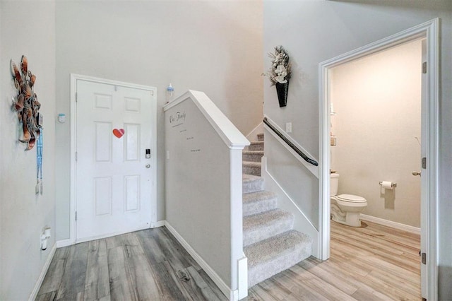 foyer featuring baseboards, wood finished floors, and stairway