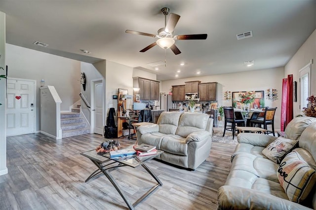 living area with ceiling fan, light wood-style floors, recessed lighting, visible vents, and stairway