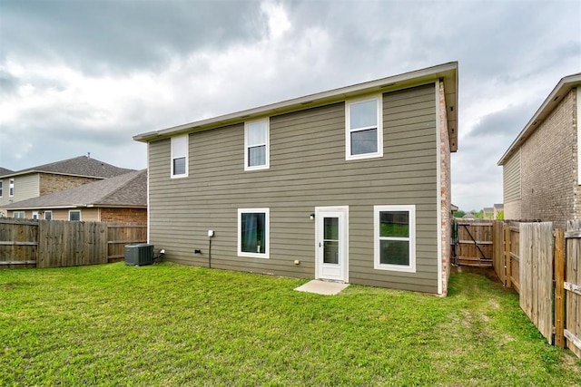 rear view of house with a fenced backyard, central air condition unit, and a yard
