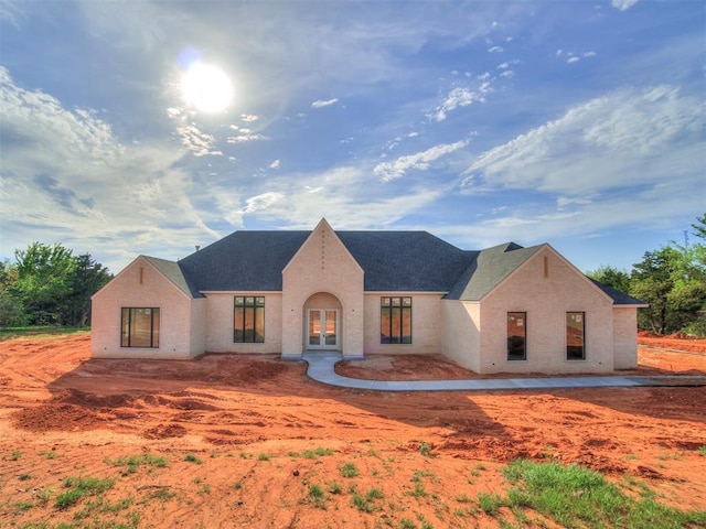 view of front facade with a shingled roof and french doors