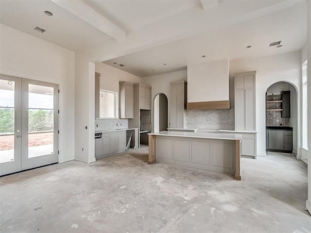 kitchen featuring premium range hood, decorative backsplash, arched walkways, and french doors