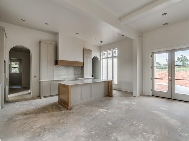 kitchen with arched walkways, plenty of natural light, and a center island