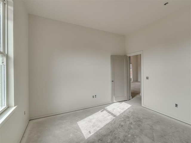 empty room with plenty of natural light and concrete flooring