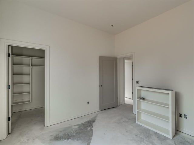 unfurnished bedroom featuring a spacious closet, concrete floors, and a closet