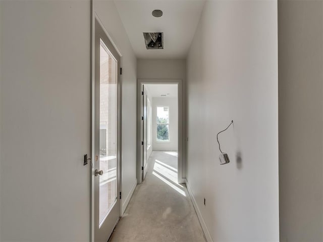 hallway with baseboards and finished concrete floors