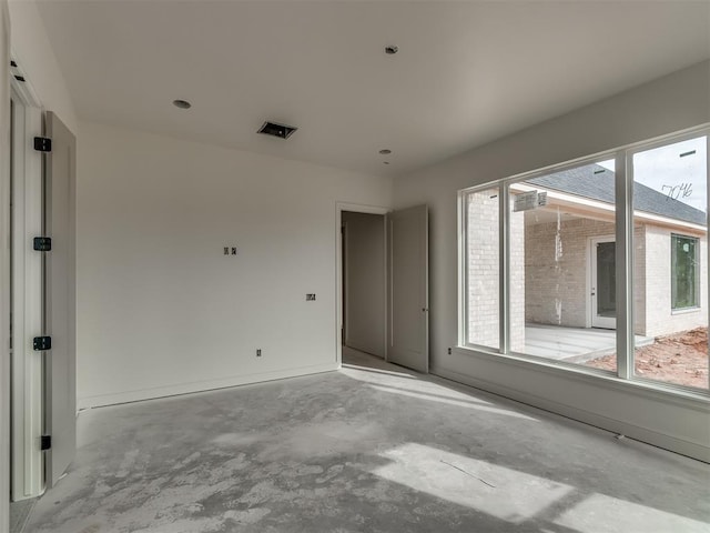 spare room featuring unfinished concrete floors, plenty of natural light, and baseboards