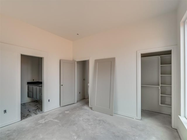 unfurnished bedroom with a spacious closet, baseboards, connected bathroom, and a closet