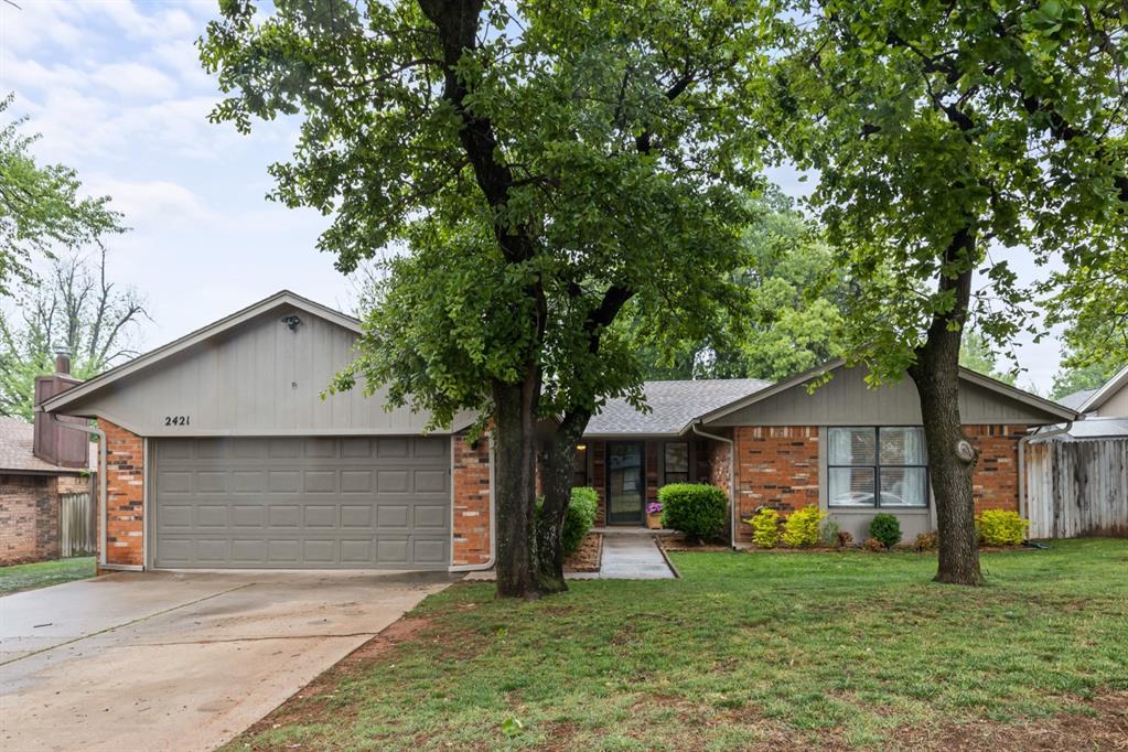 2421 Northwood Ln, Edmond, OK 73013 - single story home with concrete driveway, an attached garage, and brick siding