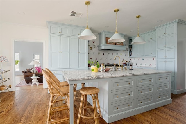kitchen with a kitchen breakfast bar, light stone countertops, visible vents, and decorative backsplash