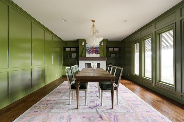 dining area featuring wood finished floors, a decorative wall, and a notable chandelier