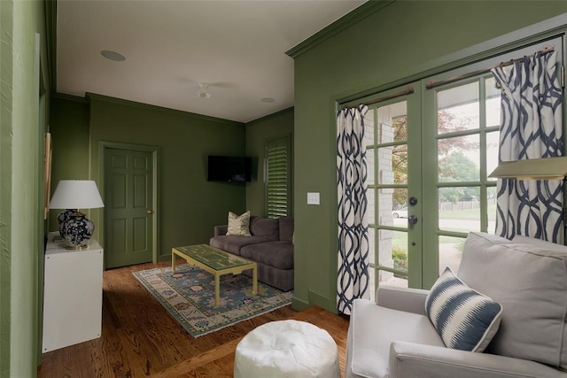 living room with crown molding, baseboards, and wood finished floors