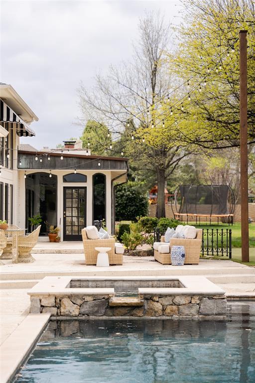 outdoor pool with a trampoline, an outdoor fire pit, and a patio area