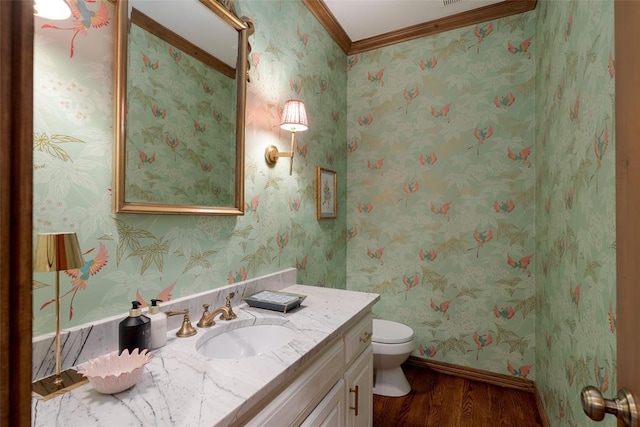 half bathroom featuring vanity, ornamental molding, toilet, and wood finished floors