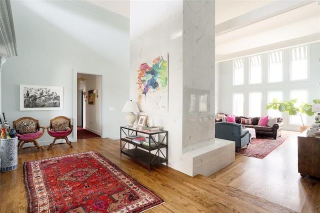 living room featuring baseboards, a high ceiling, decorative columns, and wood finished floors