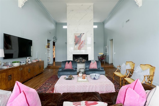 living room with crown molding, wood finished floors, and a towering ceiling
