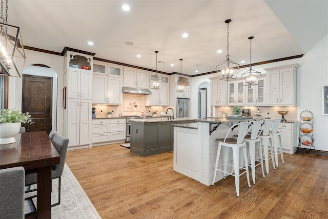4301 Frisco Bridge Blvd, Edmond, OK 73034 - kitchen with arched walkways, a spacious island, appliances with stainless steel finishes, under cabinet range hood, and crown molding