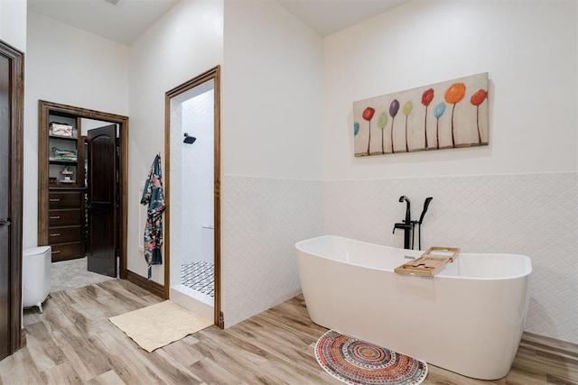 4301 Frisco Bridge Blvd, Edmond, OK 73034 - full bath featuring wood finished floors, wainscoting, a freestanding bath, tile walls, and a walk in shower