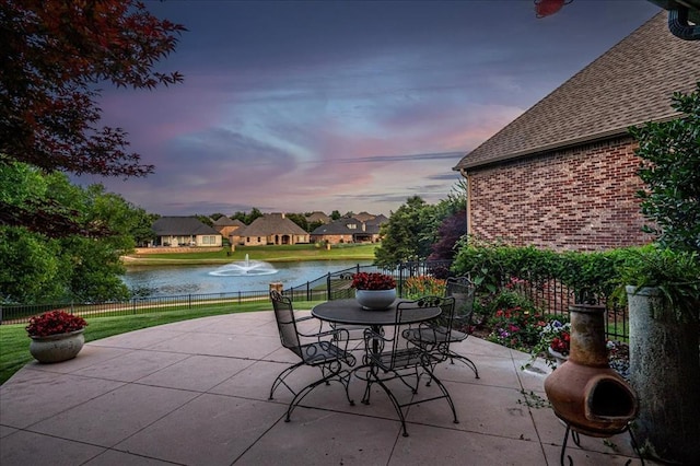 4400 The Ranch Rd, Edmond, OK 73034 - patio terrace at dusk with fence, a yard, and a water view