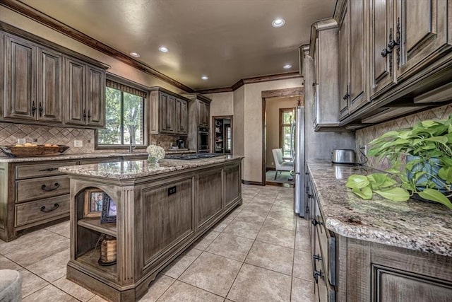 4400 The Ranch Rd, Edmond, OK 73034 - kitchen featuring light tile patterned flooring, dark brown cabinetry, backsplash, a kitchen island, and ornamental molding