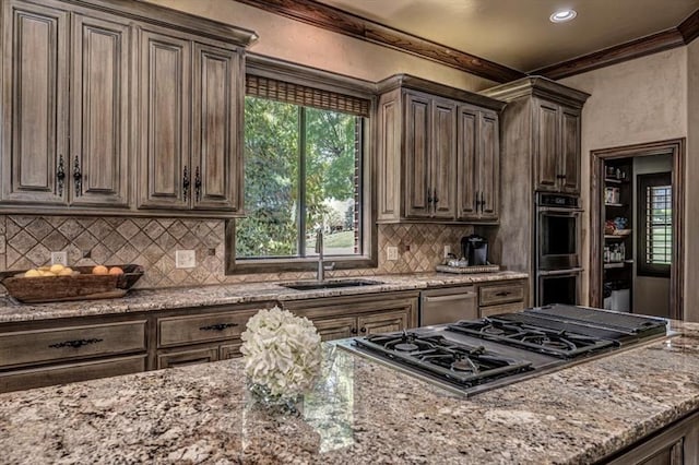 4400 The Ranch Rd, Edmond, OK 73034 - kitchen featuring dark brown cabinetry, tasteful backsplash, light stone counters, appliances with stainless steel finishes, and a sink