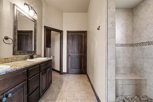 212 SW 144th, Oklahoma City, OK 73170 - bathroom featuring double vanity, a tile shower, tile patterned flooring, and baseboards