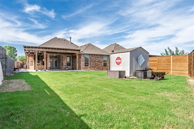 212 SW 144th, Oklahoma City, OK 73170 - back of property with a storage shed, an outdoor structure, a patio area, brick siding, and roof with shingles